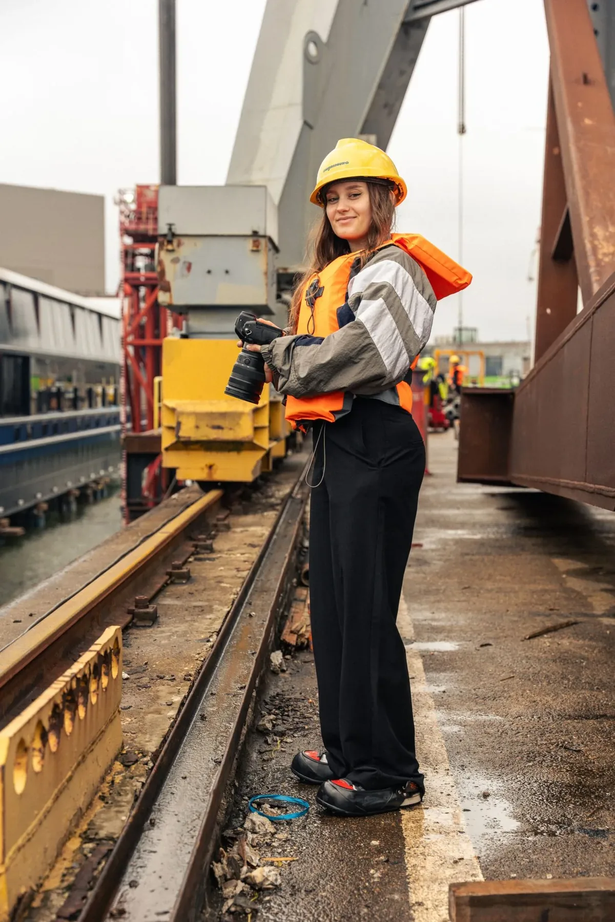 Met camera, helm en reddingsvest op een werf