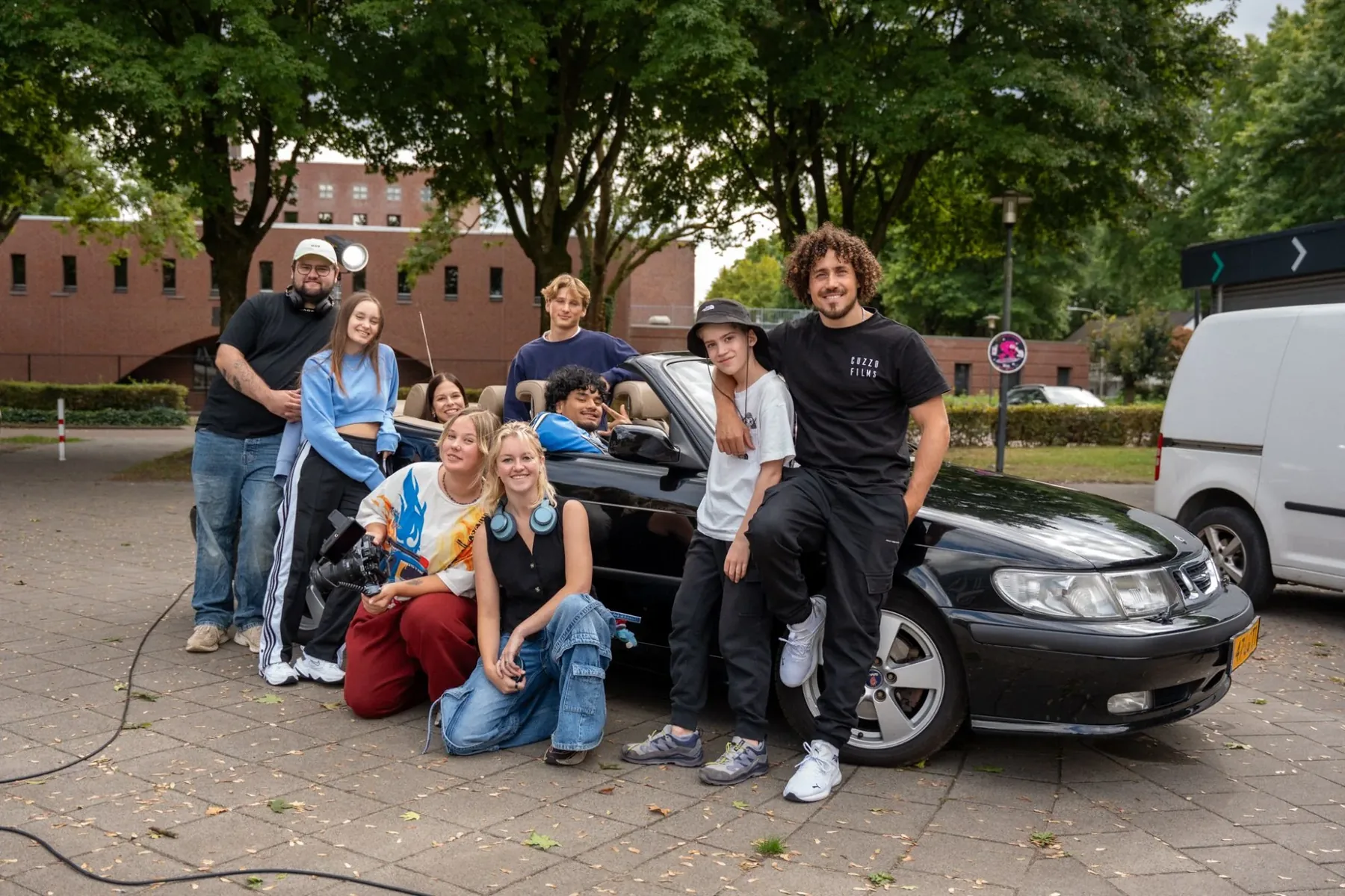 Filmcrew poseert bij een zwarte cabrio tijdens een opnamedag