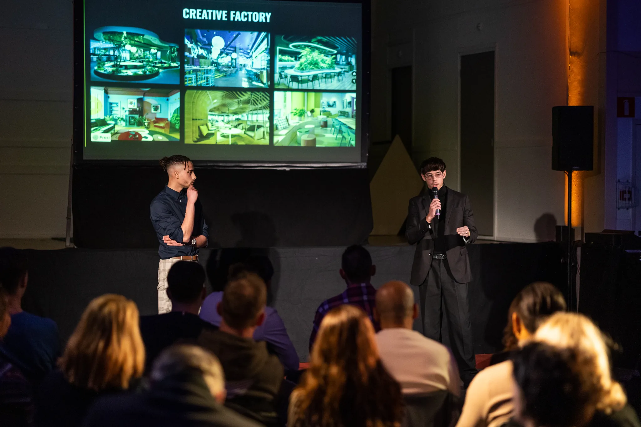 Twee sprekers op het podium in de grote zaal van SOLID, met publiek op de voorgrond