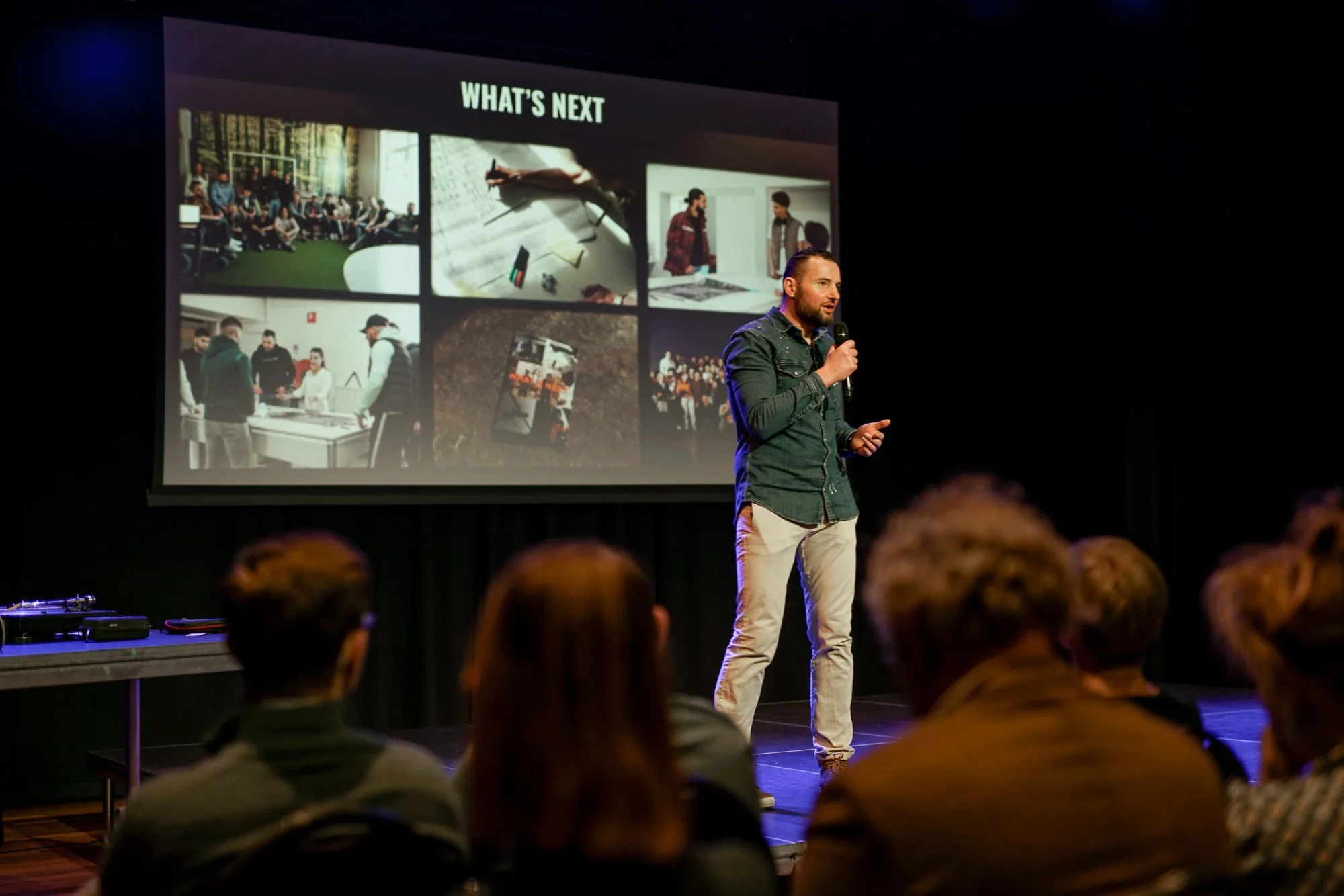 Een spreker op het podium presenteert &lsquo;What&rsquo;s next&rsquo; aan een zaal vol publiek