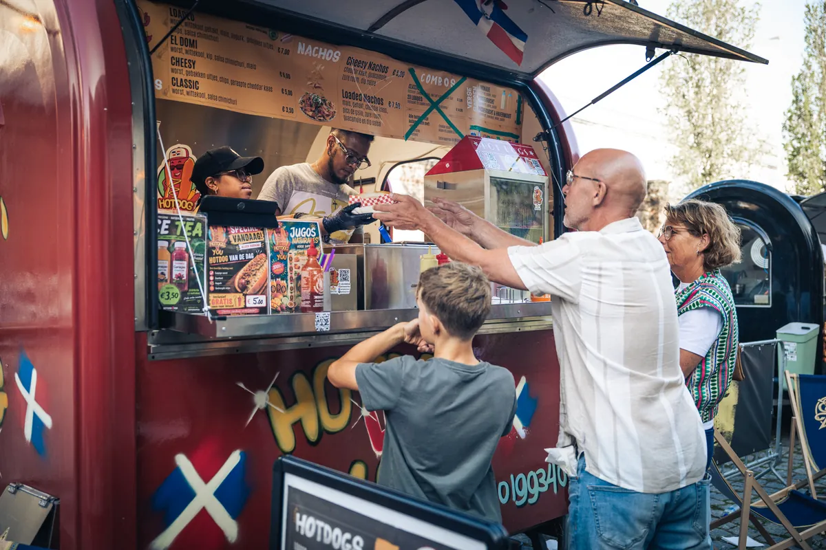 Een jongen en een man halen eten bij een foodtruck op de Foodmarket