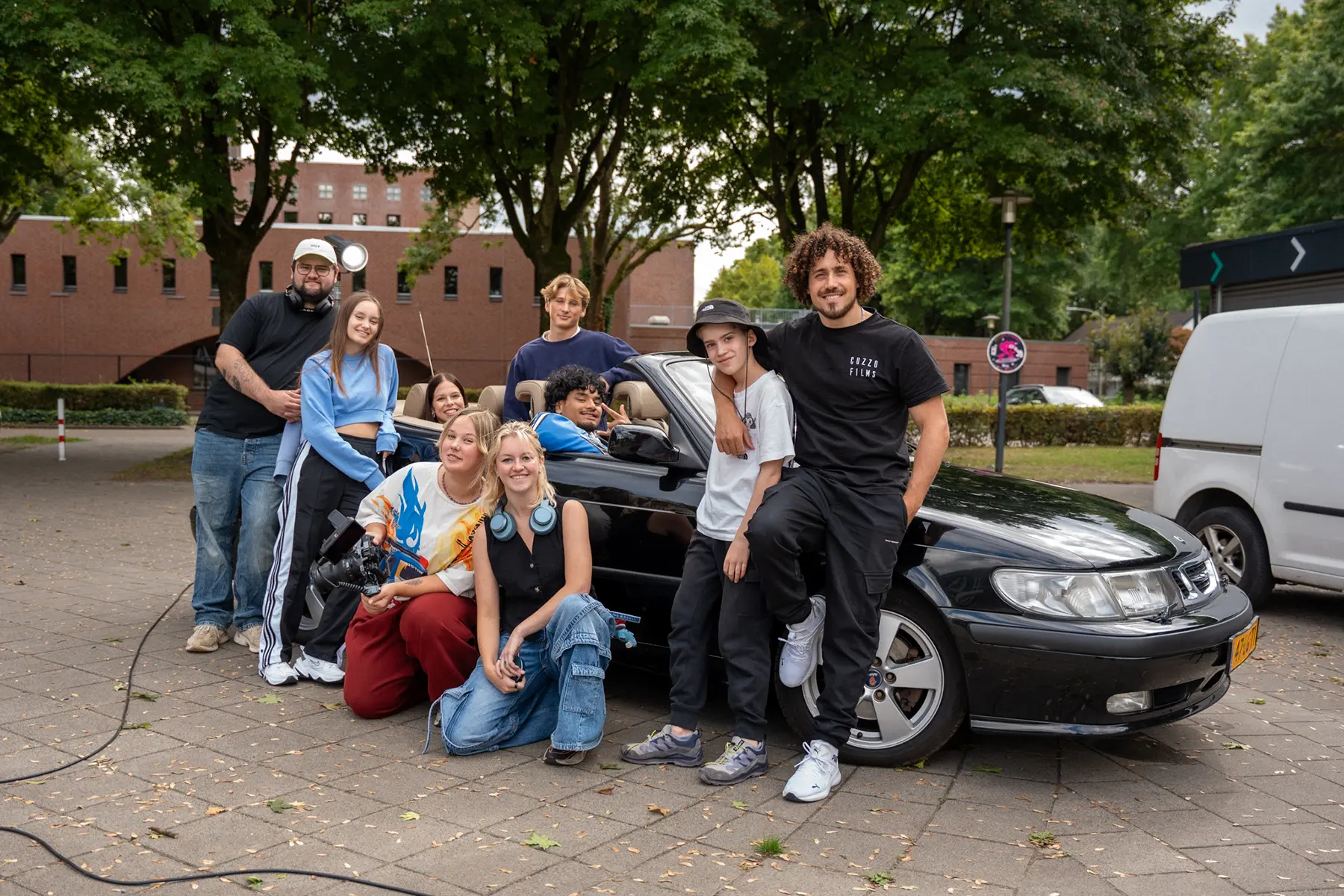 Filmcrew poseert bij een zwarte cabrio tijdens een opnamedag