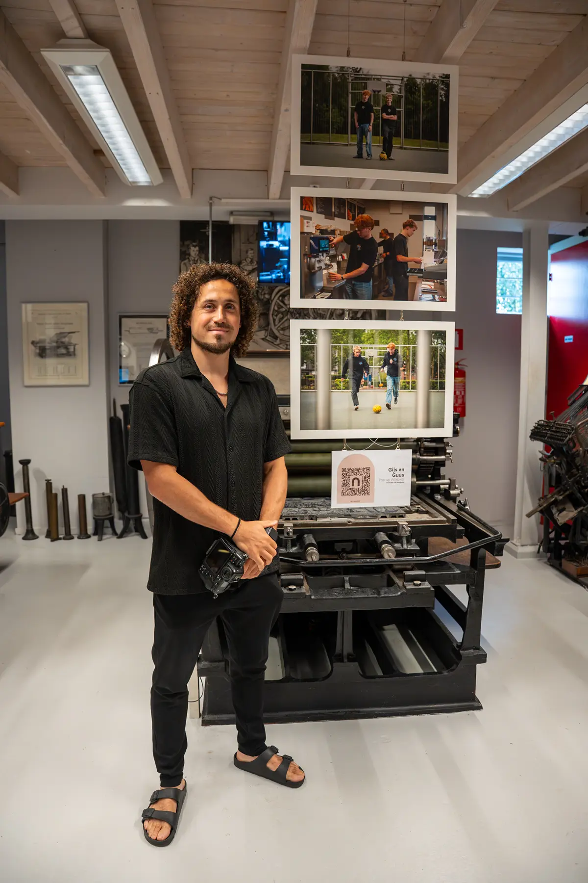 Fotoexpositie met drie portretten boven een oude drukpers