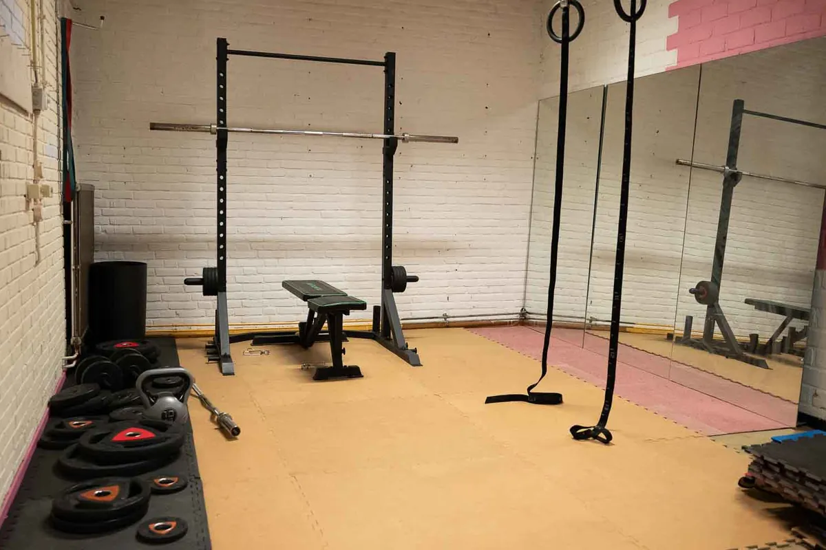 De gym met een squatrek, halters, ringen en een spiegelwand