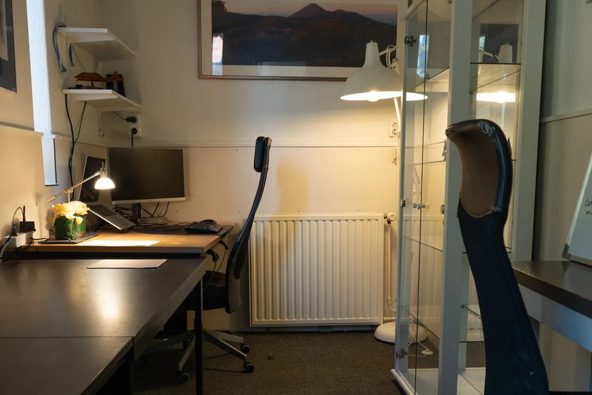 Een bureau met een scherm, een bureaulamp en een bureaustoel in de 24/7 lock-in room