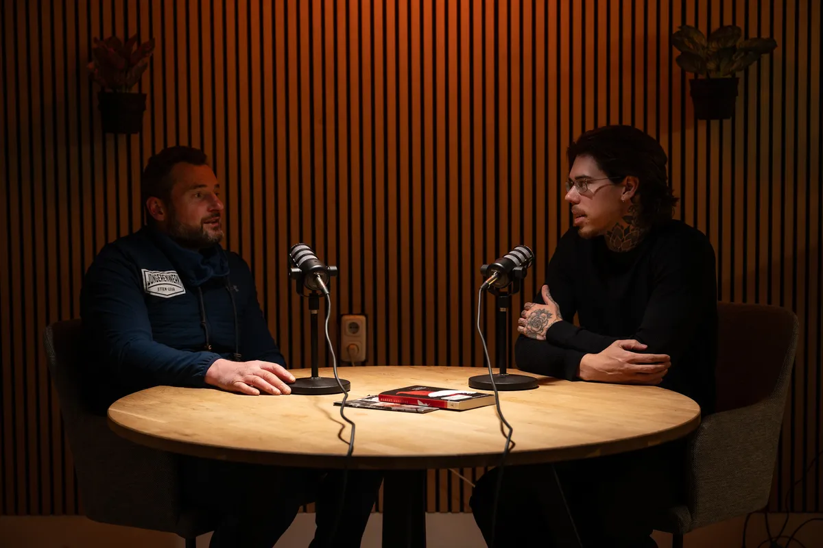 Twee mensen in gesprek aan tafel met podcastmicrofoons in de mediastudio