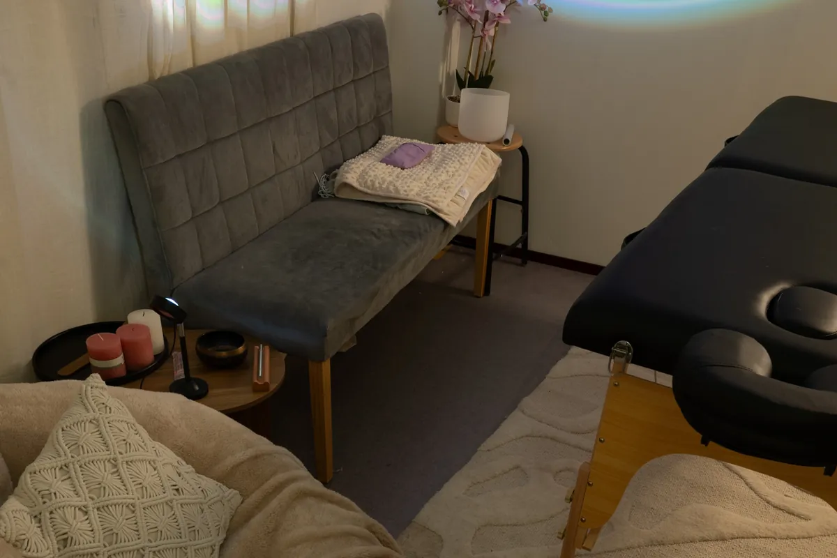 Een massagetafel, een zitzak en een bankje in zacht paars licht in de Health & Wellness Studio